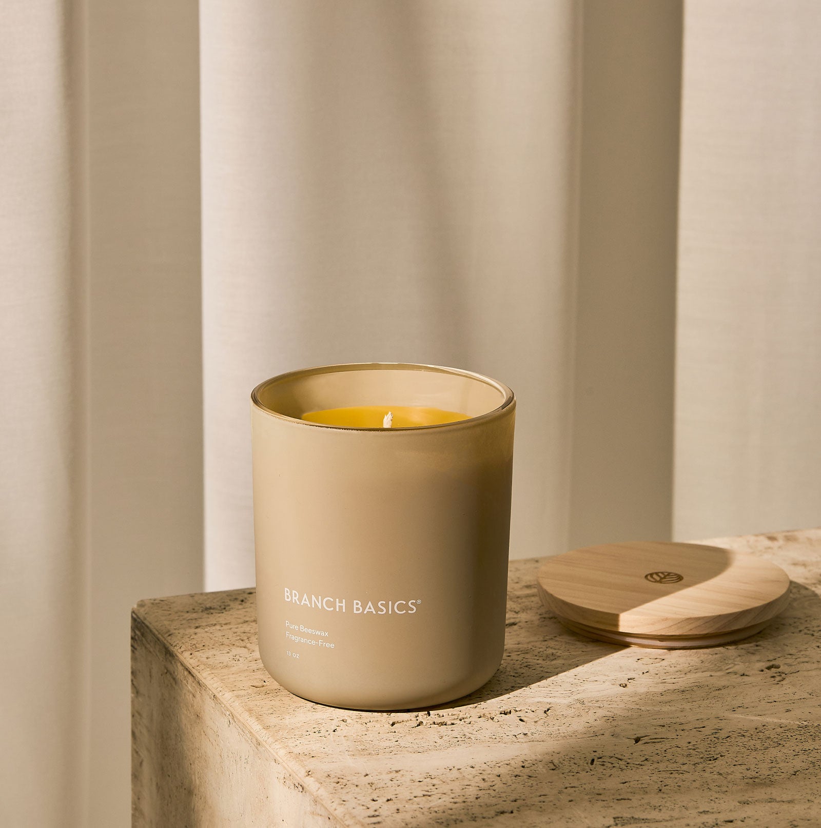 A Branch Basics 100% Beeswax Candle, housed in a glass jar with an organic cotton wick, displayed on a neutral background. - View 1
